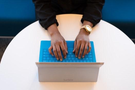 A student's hands on a blue laptop keyboard, writing a personal statement for a teaching program application