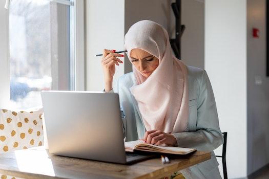 A Muslim woman sits at a laptop and studies for her TExES.