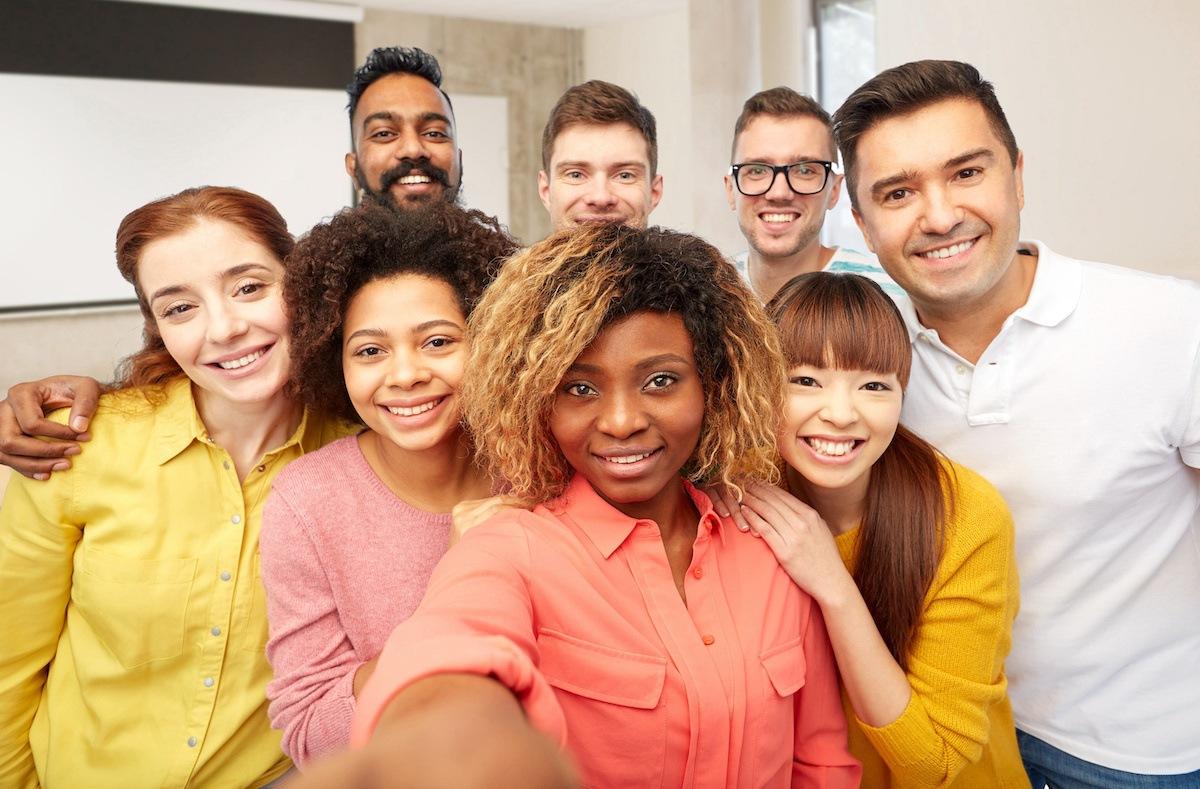 A group of eight diverse future Houston teachers gather for a group selfie. The person closest to the front holds out the camera in front of her to take the picture.